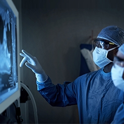 Zwei Chirurgen in Kitteln und Masken bei der Überprüfung von Bildgebungsscans