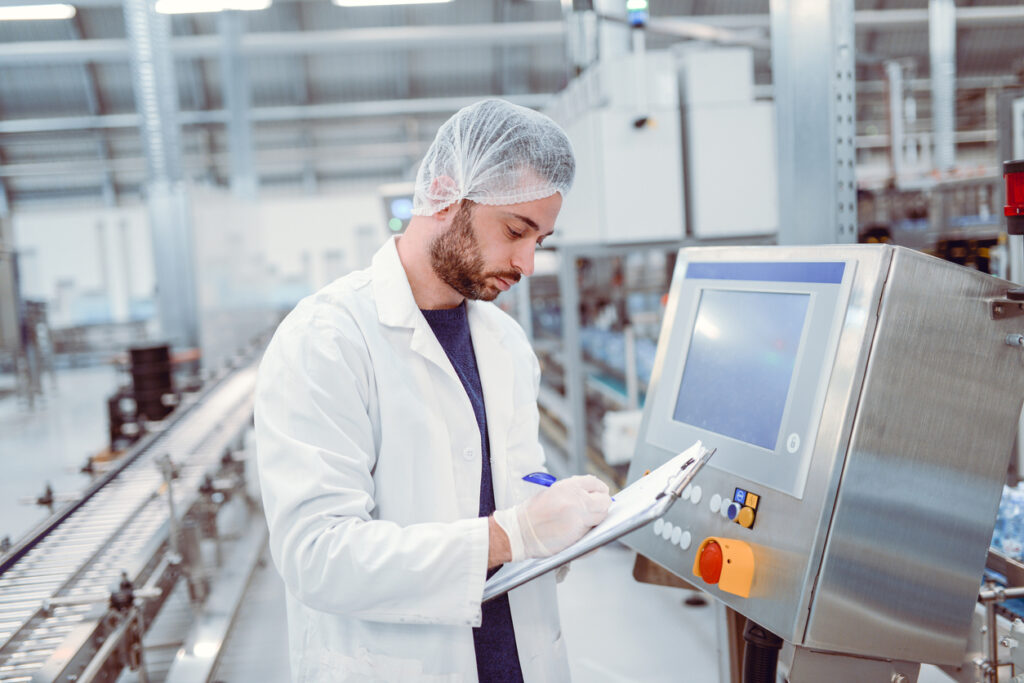 Ein Arbeiter in einem Lebensmittel- und Getränkeherstellungsbetrieb, der einen Industriecomputer auf Konformität überprüft