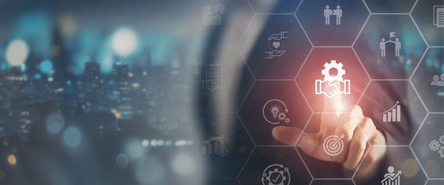 Ein Finger, der ein Zahnrad- und Handshake-Symbol auf einem AR-ähnlichen Sechseckgitter mit ähnlichen Symbolen drückt, mit einer unscharfen Stadtsilhouette bei Nacht im Hintergrund