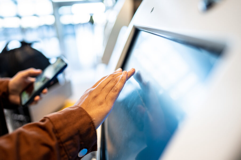 Frau tippt auf einen Kiosk-Computer mit Touchscreen