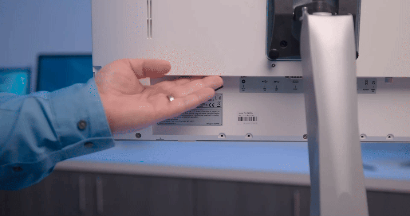 An animated GIF wherein hand removes and then inserts a hot-swappable battery pack into the bottom bay of a white Teguar computer, viewed from behind. The computer is in a serene blue room with other Teguar devices.