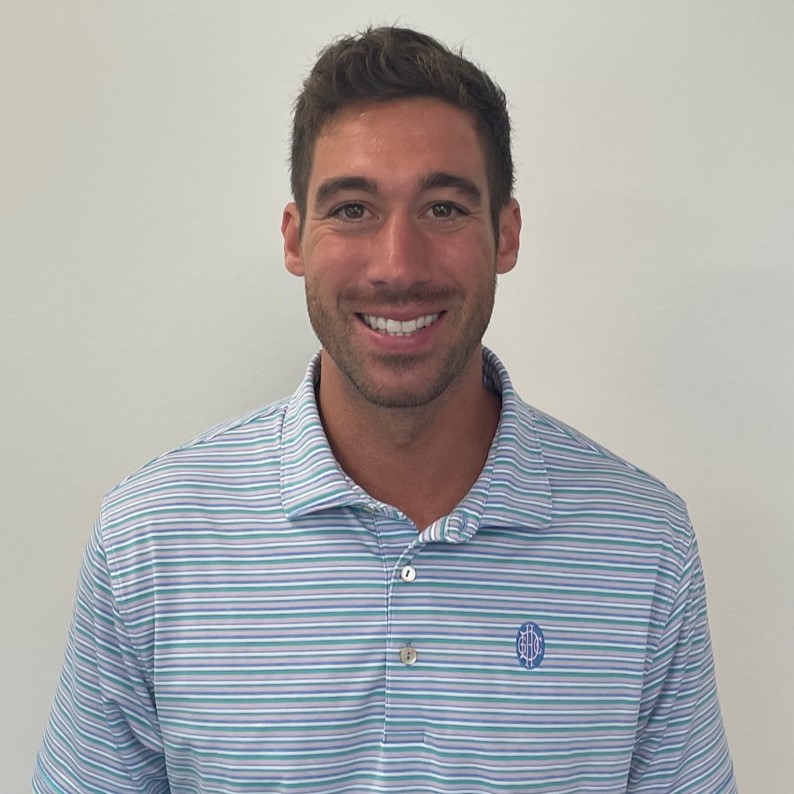 Josh McKinley lächelt in einem blau gestreiften Poloshirt in die Kamera.