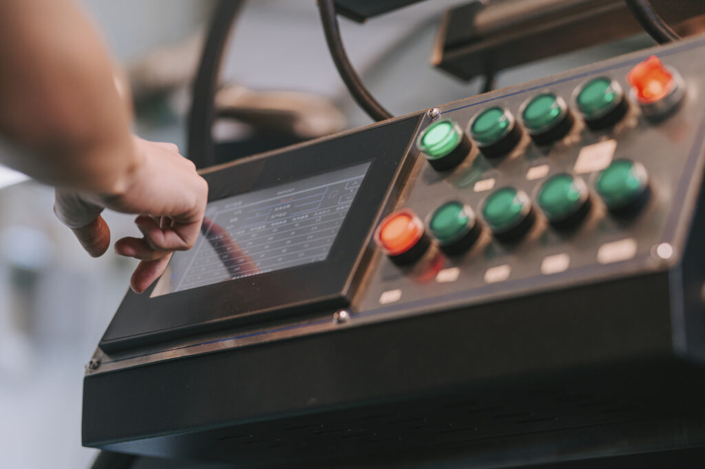 close up worker operating control panel touch screen on coffee roaster machinery preparing for coffee roasting process