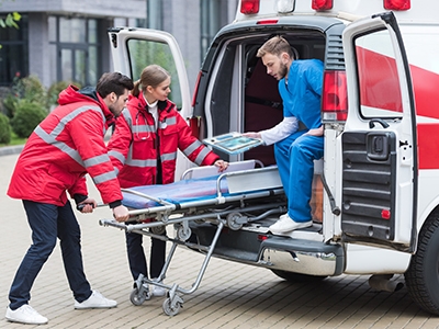 Healthcare professional using a rugged medical tablet to assist two EMTs