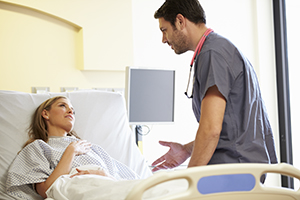 Nurse consults with patient in hospital bed with a beside terminal nearby