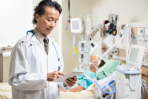 Doctor examining patient's report on medical tablet in hospital room