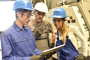Metalworker with training people using industrial tablet