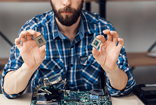Man holding two computer chips as he disassembles a computer