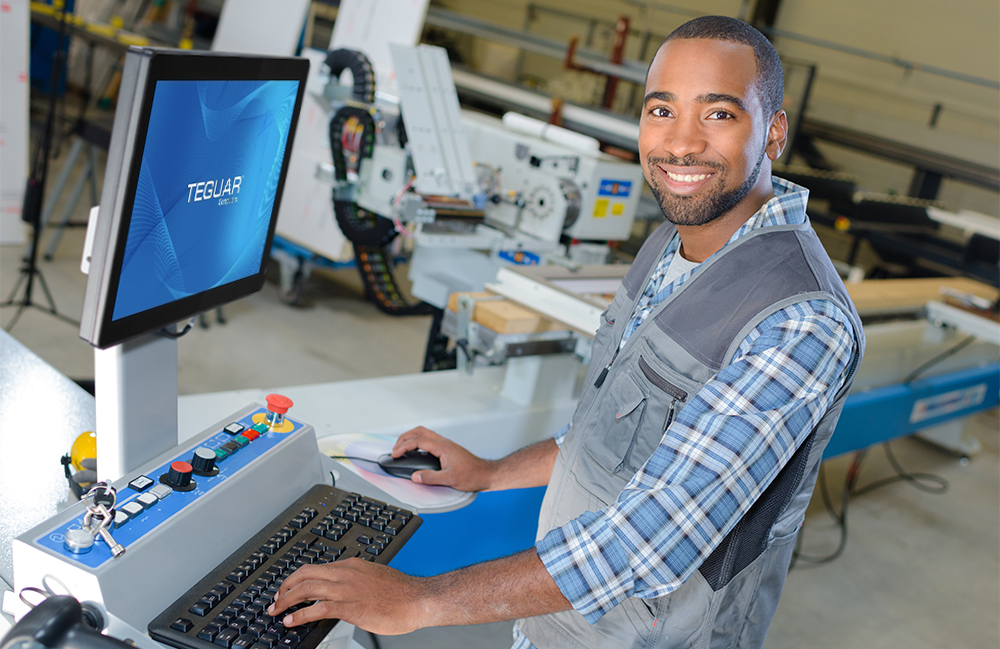A man using a fanless panel pc in an industrial environment pauses to smile