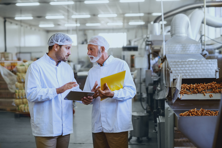 two men in food production line discussing production