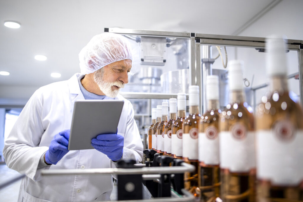 A cleanroom worker using a tablet to inspect bottles for food and beverage compliance