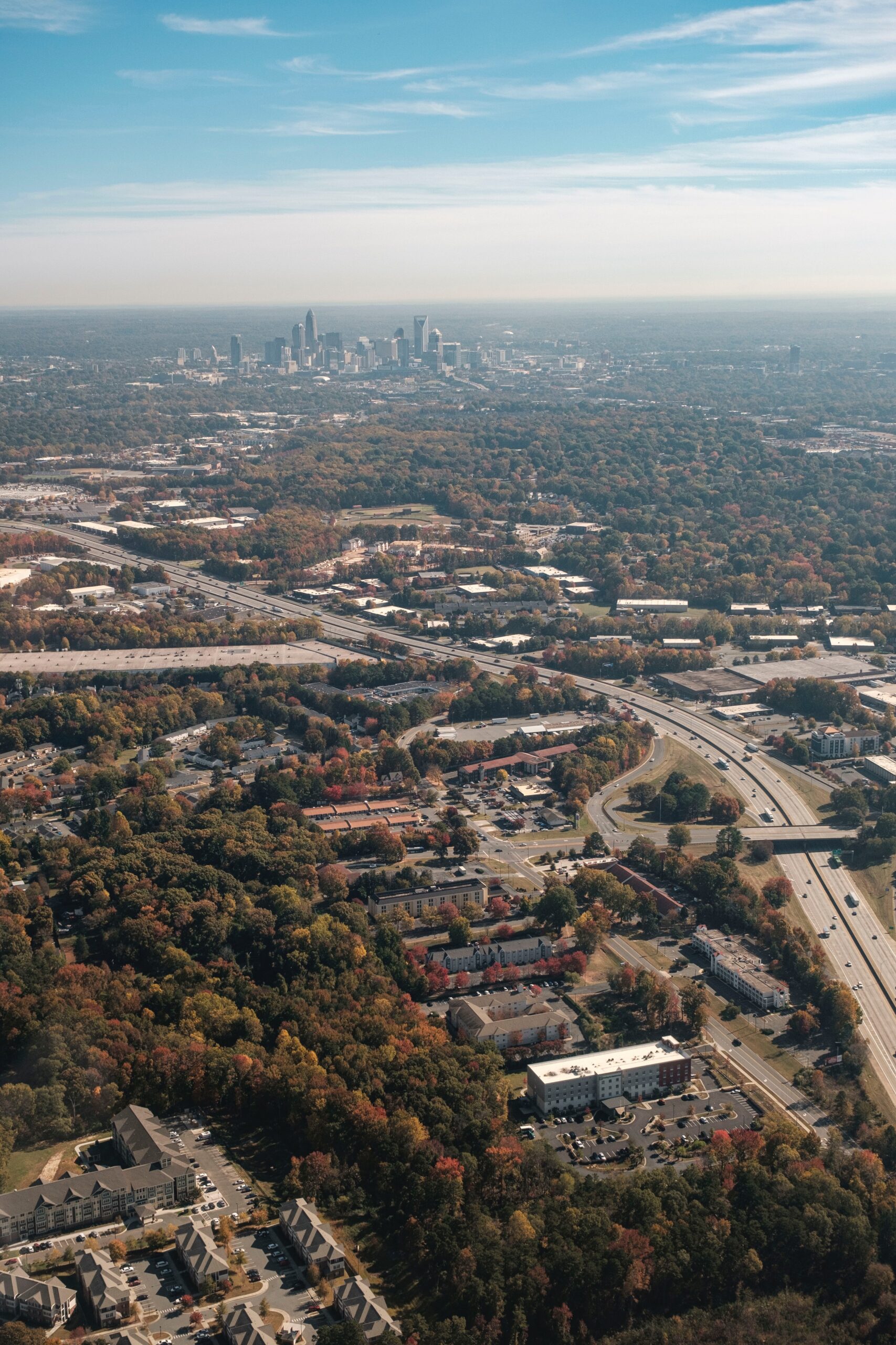 drone photography of Charlotte, NC, USA with industrial and suburban terrain in the foreground and the uptown city epicenter in the distance