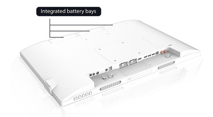 The portable medical display is resting with its front bezel downwards. The bottom of the back is tilted towards the viewer to show the input/outputs. There is a label indicating Integrated Battery Bays on the opposite (top) side of the back.