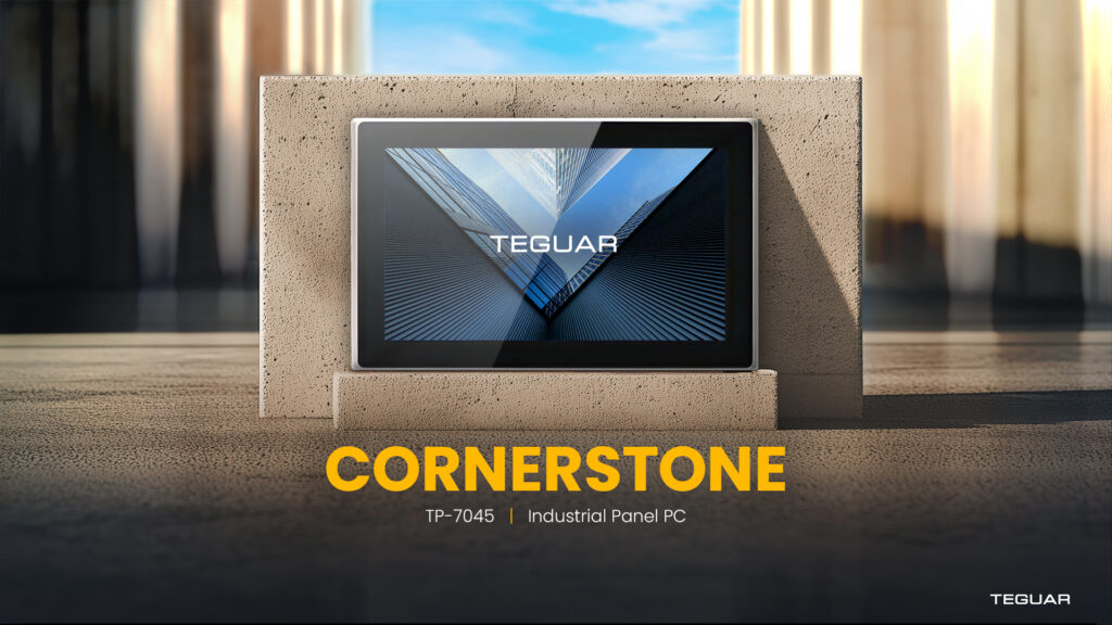 The Cornerstone Industrial Panel PC sits in front of a sandy colored brick in a bright concrete setting. Yellow sunlight casts shadows off of the computer's elegant, angular frame. The screen shows a gleaming dynamic cityscape with the title TEGUAR overlaid on it. Text on the image reads Cornerstone TP-7045 Industrial Panel PC.
