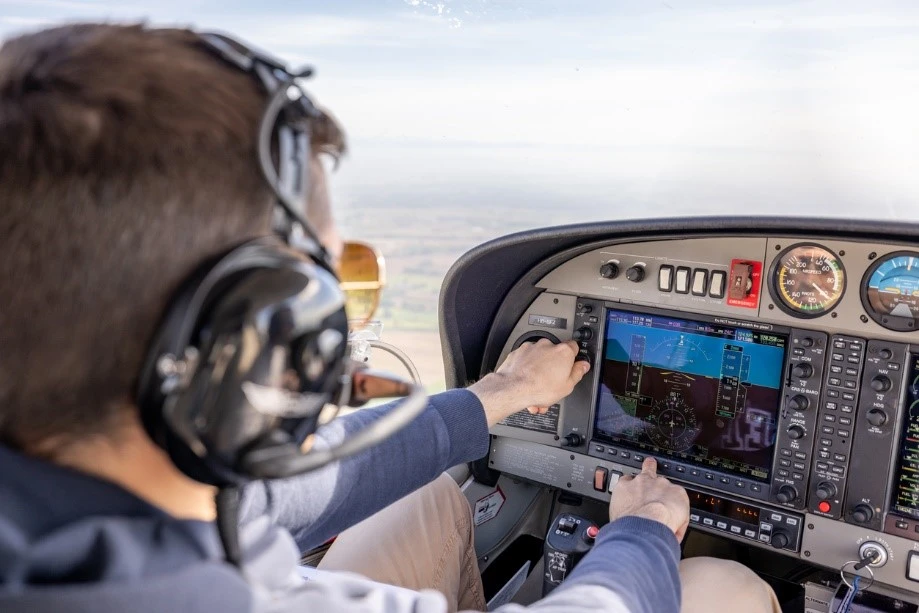 A pilot interacting with controls in a small aircraft.