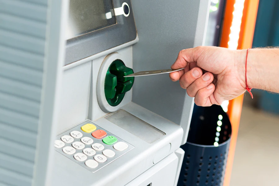 A hand inserts a card into an ATM.