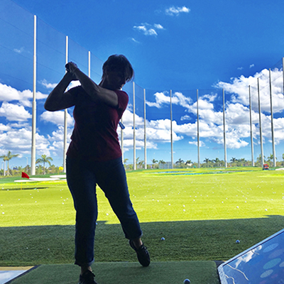 A woman winds up to drive a golf ball at the driving range.