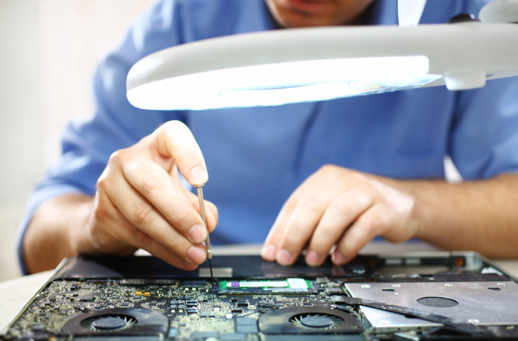 Man unscrewing motherboard of a laptop.