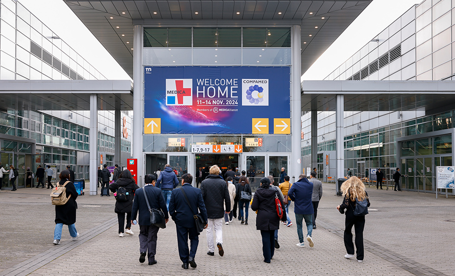 People walk into an event hall with a large sign that says Welcome Home, featuring the MEDICA and COMPAMED logos.