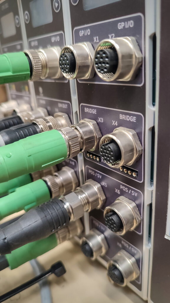 M12 metric circular connectors and cable on a rack in a measurement bay.
