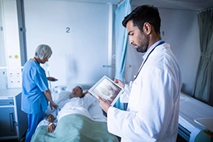 Doctor looking at medical tablet while nurse assisting a patient in hospital