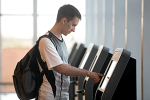 Man in airport using a public touchscreen kiosk computer