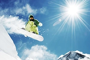 Snowboarder mid-jump under bright sunlight