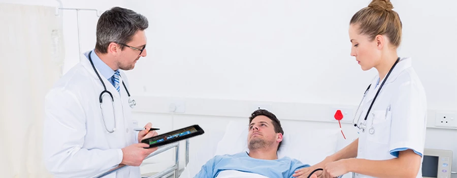 Doctor holding a rugged tablet helping a patient